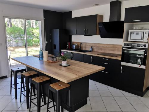 une cuisine avec une grande table en bois et des tabourets dans l'établissement Villa Résidentielle 5 Chambres Proche Plage, WiFi, Parking - FR-1-194-225, à La Faute-sur-Mer