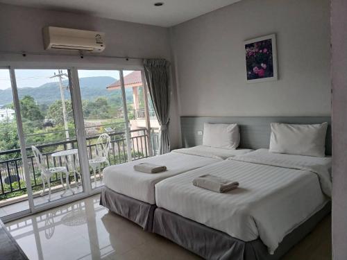 a bedroom with a large bed and a balcony at Rose Villa Hote in Pak Chong