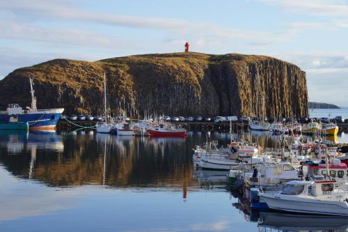 a group of boats docked in a harbor with a lighthouse at Hótel Fransiskus Stykkishólmi in Stykkishólmur