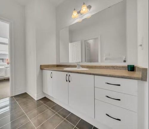 a white kitchen with a sink and a mirror at Cambridge Luxury by Ravine in Cambridge