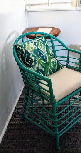 a green rattan chair with a pillow on it at Spacious Townsville City Apartment in Townsville