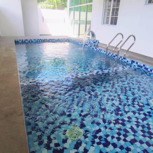 a swimming pool with blue and white tiles on the floor at Nieo Village 1 in Port Dickson