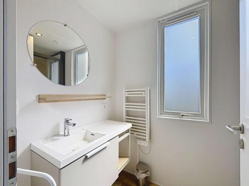 une salle de bain blanche avec un lavabo et un miroir dans l'établissement Mobil-home Keywest: 2 chambres, 2 sdb, plage à 200m, piscine chauffée, fitness, parking, Wi-Fi inclus - FR-1-361A-27, à Jullouville