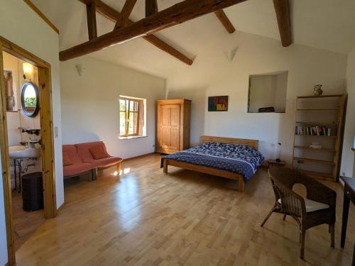 une chambre avec un lit et un canapé dans une pièce dans l'établissement Gîte paisible avec jardin et possibilité d'animaux à Gruey-lès-Surance - FR-1-589-814, à Gruey-lès-Surance