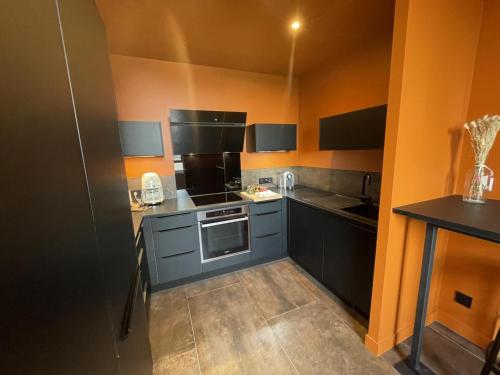 a kitchen with black and orange walls and a stove at Gîte de Charme à Avoine avec Spa Privé et Jardin - FR-1-381-621 in Avoine