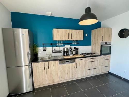 une cuisine avec des armoires en bois et un réfrigérateur en acier inoxydable dans l'établissement Maison neuve pour couple près plage des Dunes avec parking - FR-1-231-338, à Bretignolles-sur-Mer