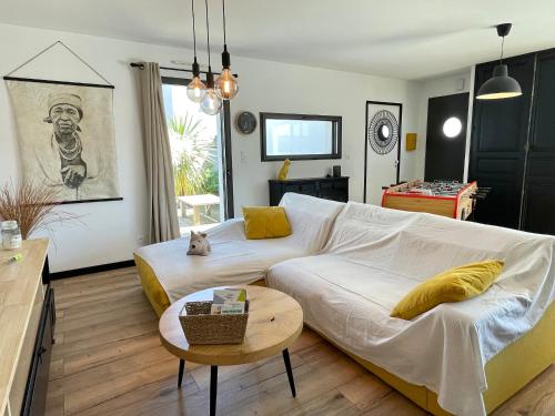 - un salon avec un grand canapé blanc et une table dans l'établissement Maison neuve pour couple près plage des Dunes avec parking - FR-1-231-338, à Bretignolles-sur-Mer