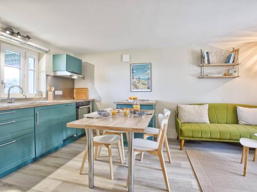 une cuisine avec une table et un canapé vert dans l'établissement Villa VertMer : Évasion paisible entre plénitude et plage - FR-1-788-71, à Varaville