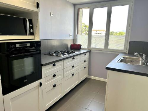 La cuisine est équipée de placards blancs et d'un four avec plaques de cuisson noires. dans l'établissement Appartement climatisé à Fréjus, parking privé - FR-1-226A-208, à Fréjus