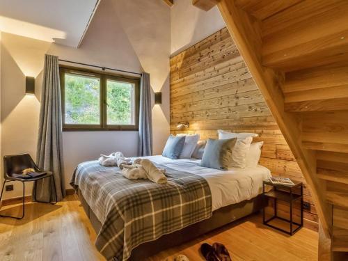 une chambre avec un grand lit avec un mur en bois dans l'établissement Appartement moderne avec jacuzzi et sauna - Les Saisies - FR-1-810-32, à Hauteluce