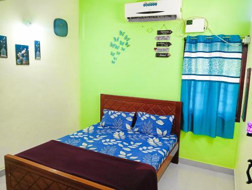 a bedroom with a bed with blue and white sheets at JAS HOMESTAY MADURAi in Tirupparangunram
