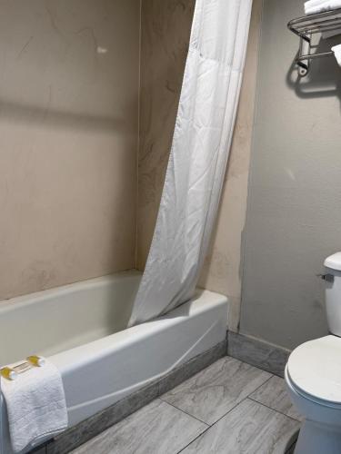 a bathroom with a tub and a toilet with a shower curtain at Days Inn by Wyndham Ontario Airport in Ontario