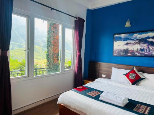 a blue bedroom with a bed and a large window at Catcat Garden House in Sa Pa