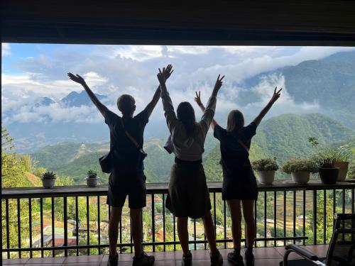 three people standing on a balcony with their hands up at Catcat Garden House in Sa Pa