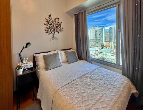 une chambre avec un lit et une grande fenêtre dans l'établissement Daily Rental Units in 8 Adriatico Manila, à Manille