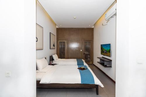 a bedroom with a large bed and a tv at Elsewhere Hotel Inn North Street Branch in Pingyao