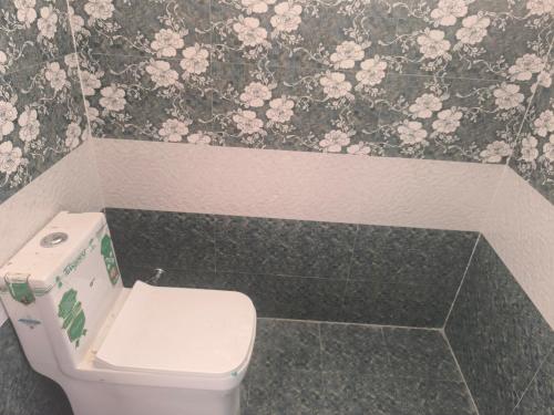 a bathroom with a toilet and flowers on the wall at Orraica Stays Aurum Vajra in Haidar Sāhibgūda