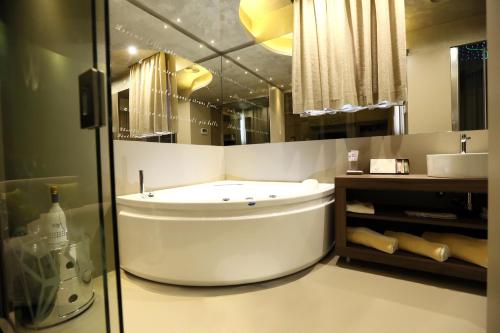 a bathroom with a large white tub and a mirror at Hotel Smeraldo in Qualiano