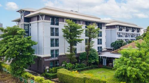 an apartment building with trees in front of it at โรงแรมสินสิริ ปัญญา-รามอินทรา in Bangkok