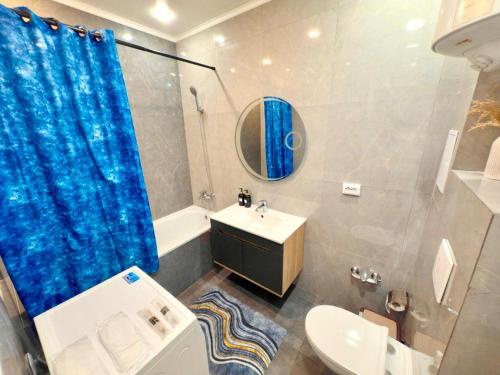 a bathroom with a blue shower curtain and a sink at Ауельбекова 120 in Kokshetau