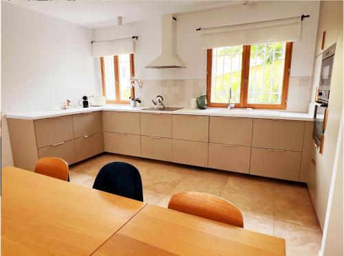 une cuisine avec des armoires blanches, une table et une fenêtre dans l'établissement Villa moderne jardin parking centre Hyères, à Hyères