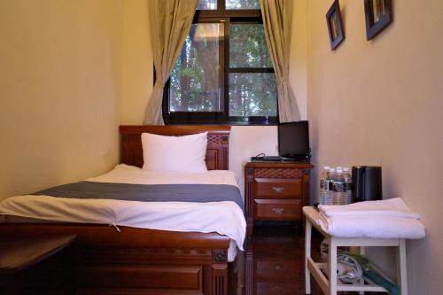 a small bedroom with a bed and a window at Meinong Yun Shanju Homestay in Meinong