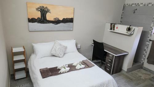 a bedroom with a bed with white sheets and a desk at Magalies River Country Retreat in Skeerpoort