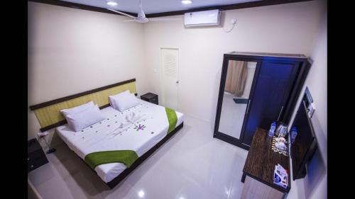 a bedroom with a bed and a mirror in it at Ari Stay Thoddoo in Thoddoo