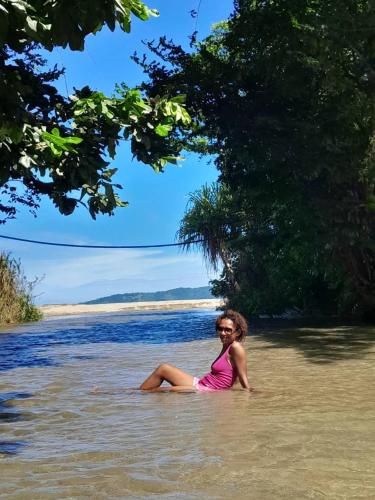 a woman sitting in the water on a beach at J60 Beach Guest House in Asini