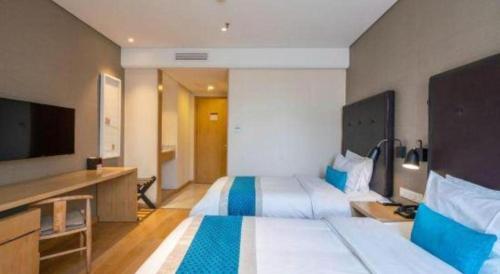 a hotel room with two beds and a flat screen tv at Yitel Shenyang Sanhao Street Shengjing Hospital in Shenyang