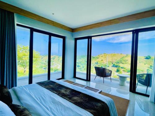 a bedroom with a bed and large glass windows at Truntum Boutique Mandalika in Kuta Lombok