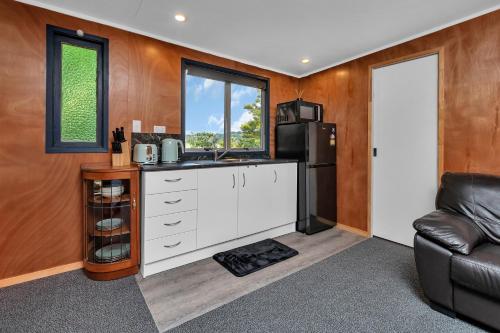 a kitchen with a sink and a refrigerator at Tui Cottage - Waipu Holiday Retreat in Waipu