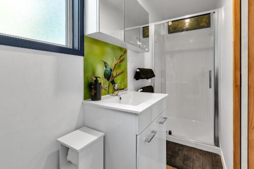 a white bathroom with a sink and a shower at Tui Cottage - Waipu Holiday Retreat in Waipu