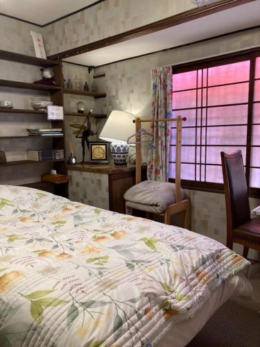 a bedroom with a bed and a desk and a window at ゲストハウス町家はま in Izumi-Sano