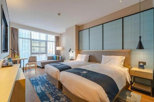 a bedroom with a large bed and a large window at Echarm Hotel Hefei West Qilitang Metro Station in Hefei