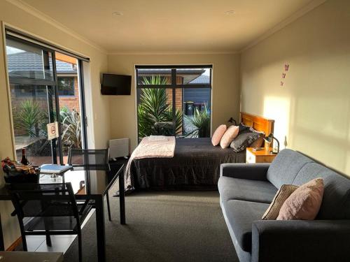 Un dormitorio con una cama y una sala de estar con un sofá. en Modern BNB unit with Wifi and Breakfast, en Greymouth