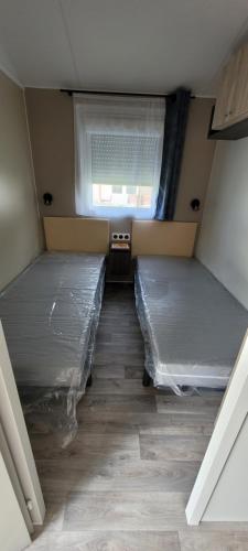 Cette chambre mansardée comprend 2 lits et une fenêtre. dans l'établissement mobil home, à Pont-Aven