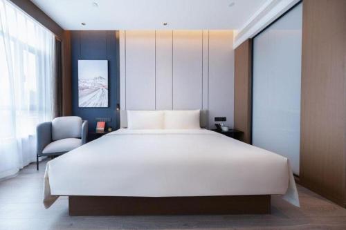 a bedroom with a large white bed and a chair at Atour Hotel Jinan Tangyan Century Avenue in Jinan