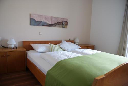 a bedroom with a bed with white and green sheets at Gasthof Albergo Kreuzwirt in Fiè