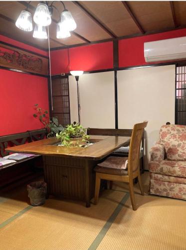 a dining room with a wooden table and a chair at ゲストハウス町家はま in Izumi-Sano