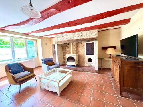 un salon avec une cheminée en pierre et une télévision dans l'établissement Maison de charme & pierre du Lot, à Blars