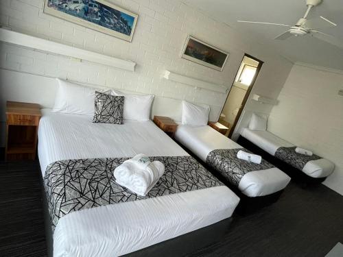 a hotel room with two beds and a couch at Coastal Bay Motel in Coffs Harbour