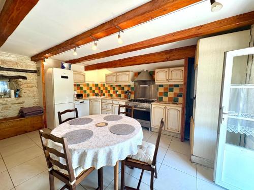 une cuisine avec une table et un réfrigérateur dans l'établissement Maison de charme & pierre du Lot, à Blars