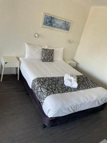 a hotel room with a bed with two towels on it at Coastal Bay Motel in Coffs Harbour