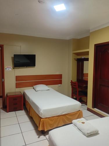 a hotel room with two beds and a flat screen tv at Hostal Saloah in Machala