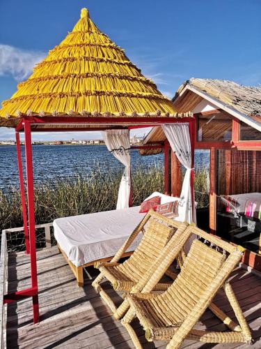 a bed and two chairs on a dock with a gazebo at Uros Qota Uta in Puno