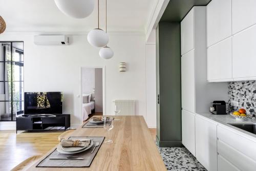 une cuisine avec des armoires blanches et une table en bois dans l'établissement Appartement Élégant à deux pas des Champs-Elysées, à Paris