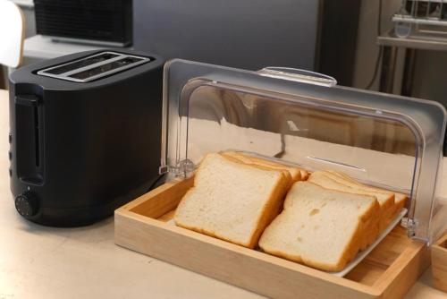 a loaf of bread in a clear container next to a toaster at Kuha Phuket Old Town in Phuket Town