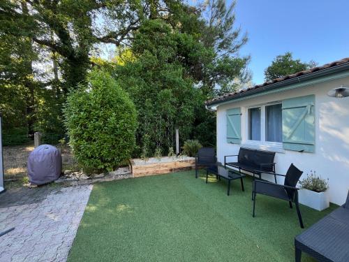 une cour avec une pelouse, des chaises et une maison dans l'établissement La Petite Suzette, à 2min à pied de la plage !, à Lanton