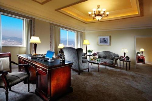 a living room with a desk with a laptop on it at New Century Hotel Taizhou 